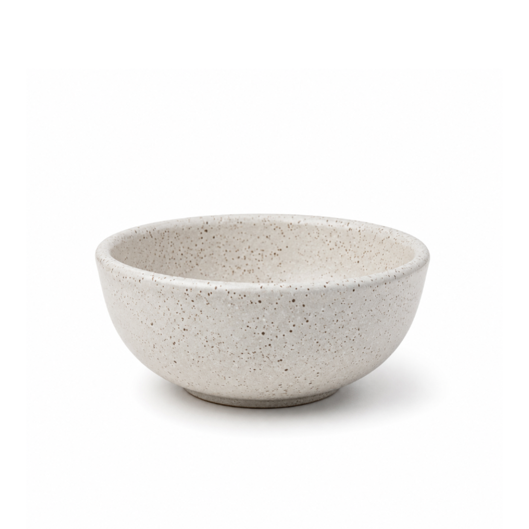 A speckled ceramic bowl in a light beige-gray color with dark brown and black flecks, shown on a clean white background.