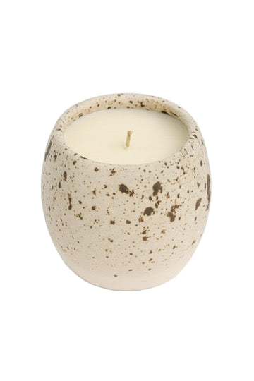 Speckled ceramic candle holder with a lit candle on a white background