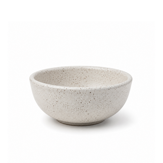 A speckled ceramic bowl in a light beige-gray color with dark brown and black flecks, shown on a clean white background.