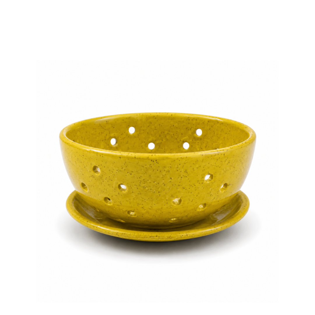 A yellow speckled ceramic colander with a matching saucer, photographed on a clean white background.