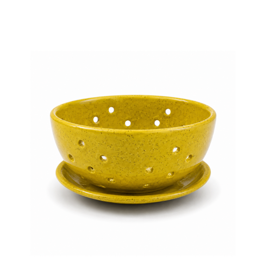 A yellow speckled ceramic colander with a matching saucer, photographed on a clean white background.