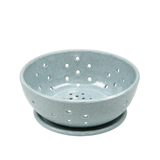 A speckled light blue ceramic berry bowl with a matching saucer, photographed on a clean white background.