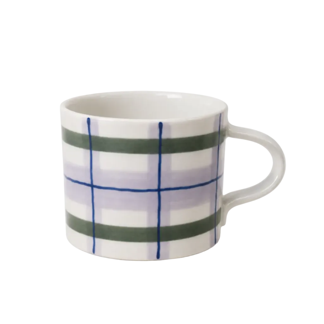 A white ceramic coffee mug with a hand-painted plaid pattern featuring green, light purple, and blue lines, set against a plain white background.