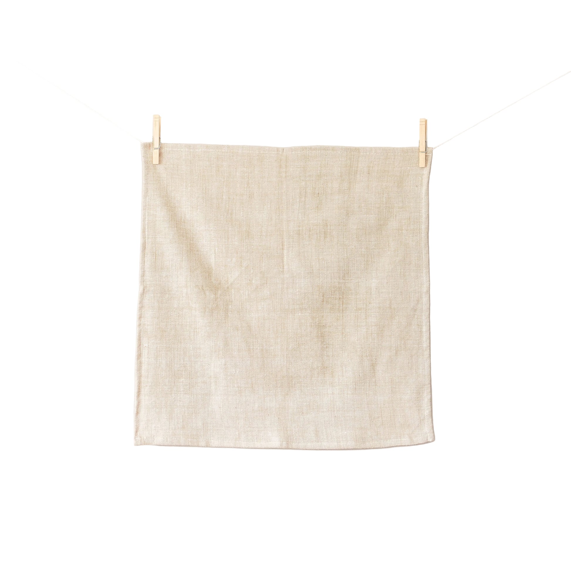 Beige towel hanging on a clothesline against a white background