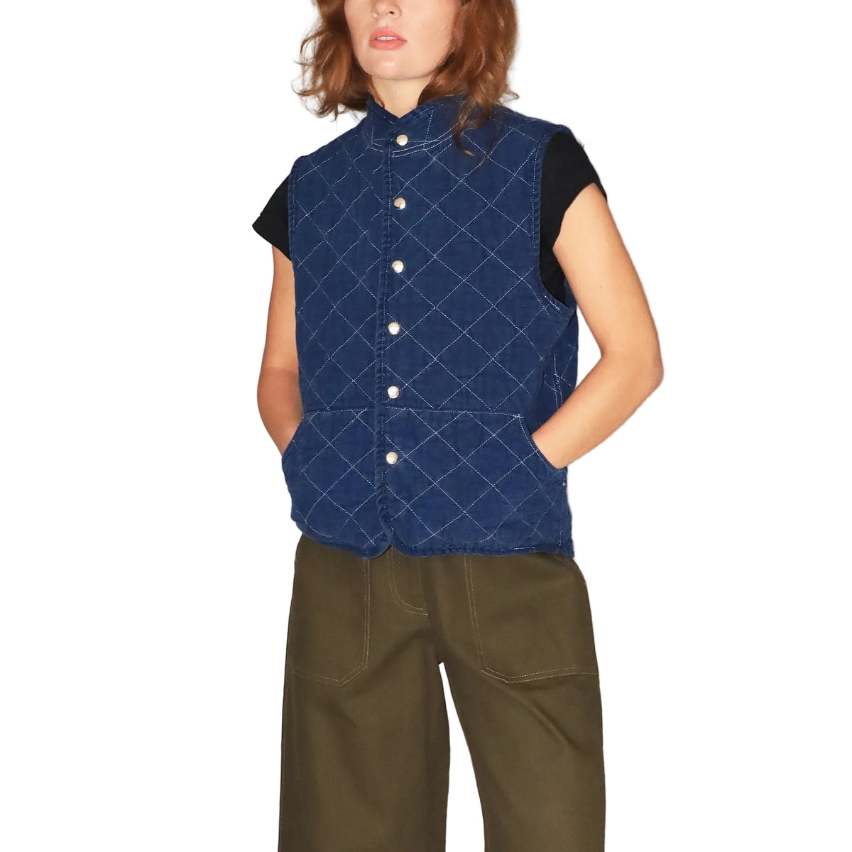 Person wearing a blue quilted vest with white buttons on a plain background