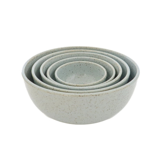 A set of 5 light blue stoneware nesting bowls of various sizes, placed stacked in an ascending order with the smallest at the bottom.